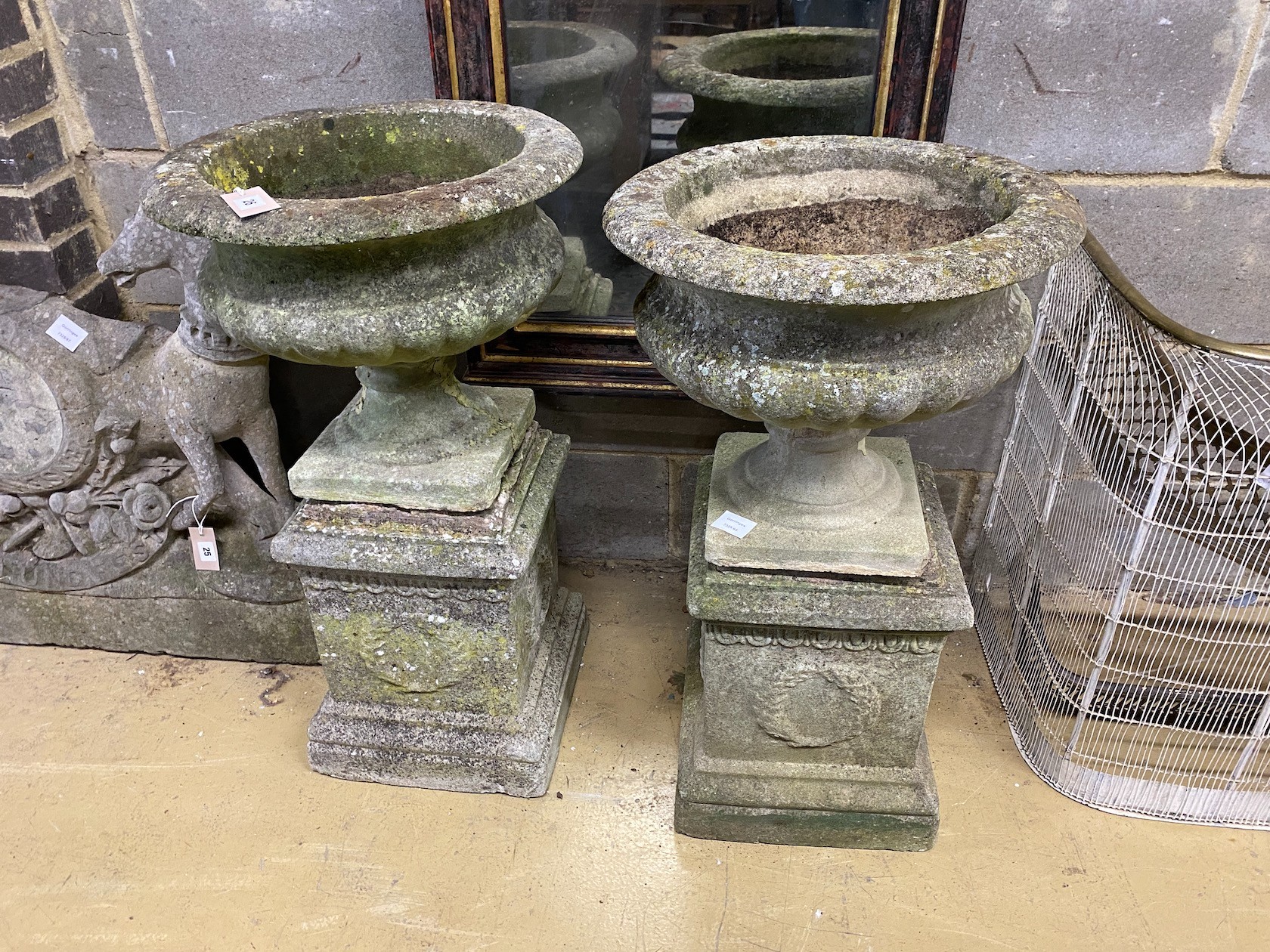 A pair of circular reconstituted stone campana garden urns on square plinths, one urn a.f., diameter 45cm, height 80cm